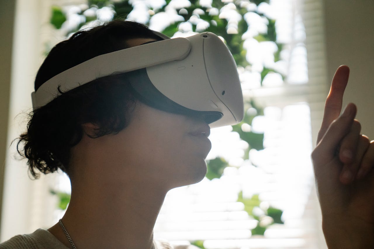 Side view of curious young male teenager in casual clothes and VR goggles looking at finger while watching interactive video