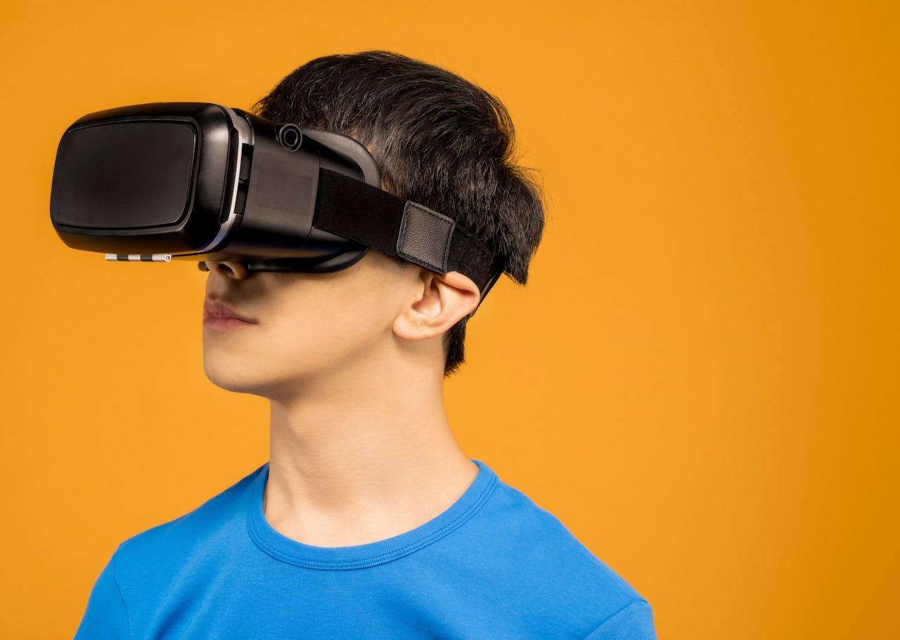 A young man wearing a VR headset immerses in virtual reality against a vibrant orange background.